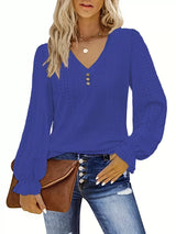 Woman wearing a blue long-sleeve top with a brown clutch on a white background