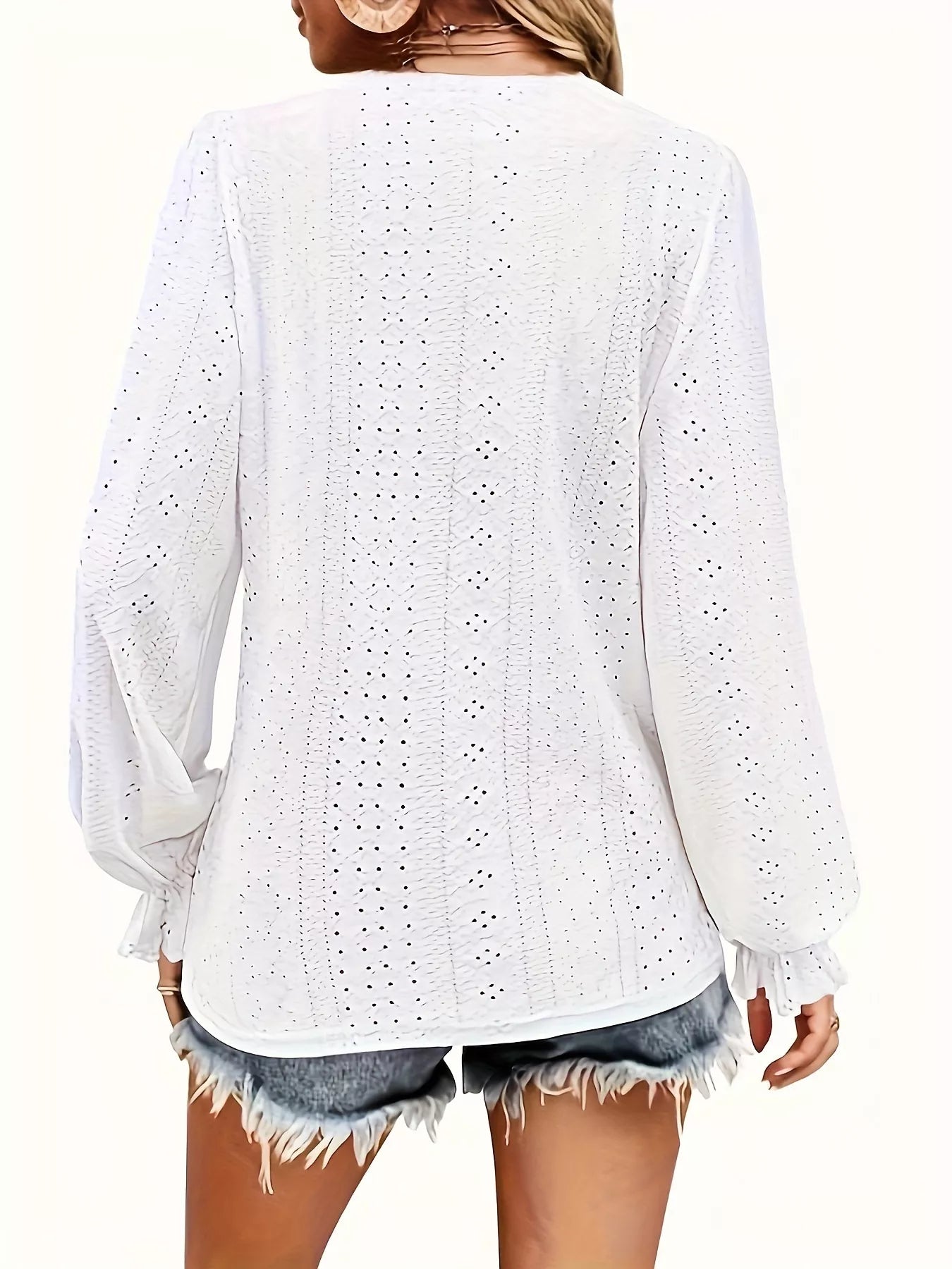 White lace top worn by a person on a white background showing back of blouse