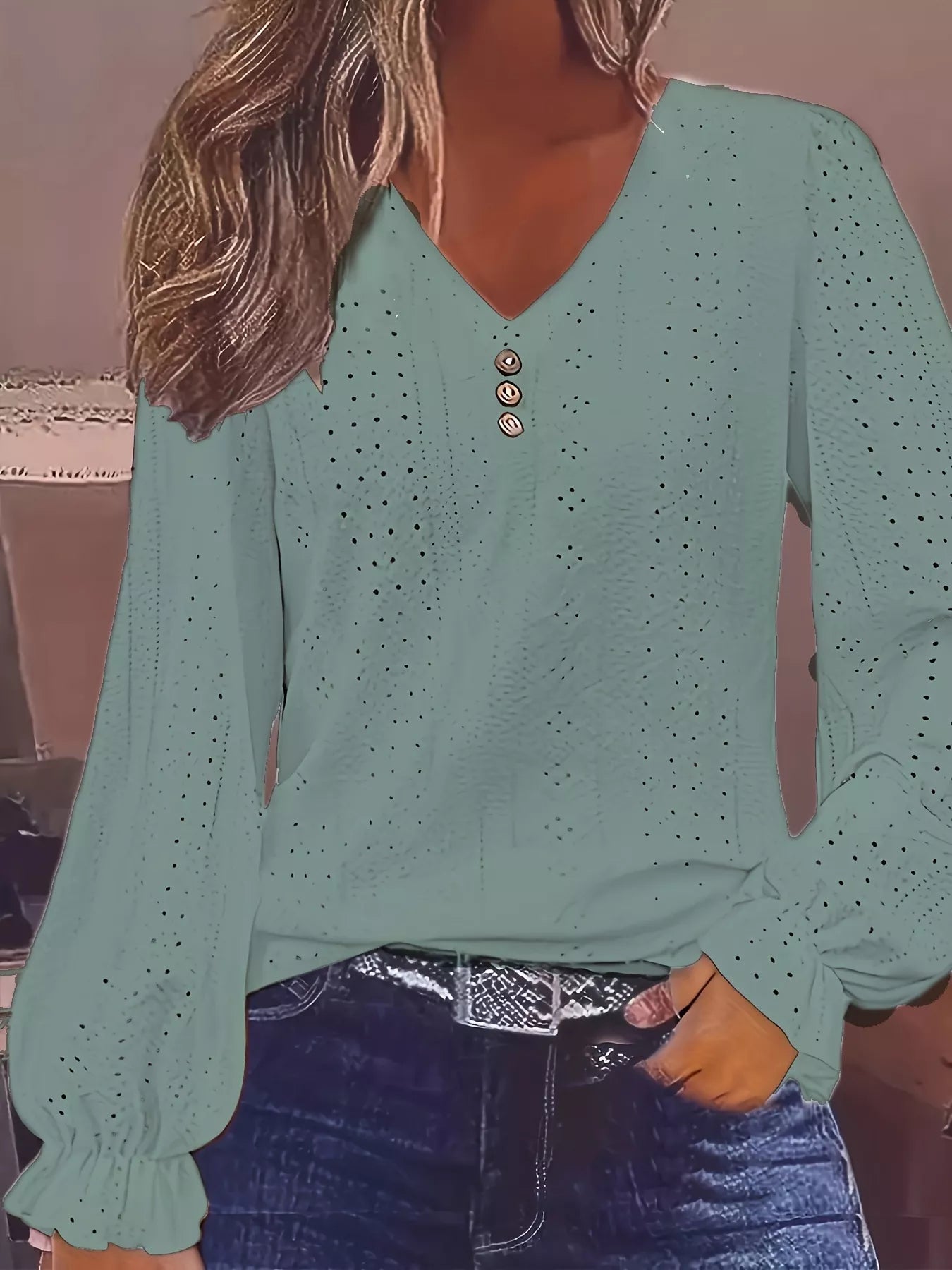 Green long-sleeve top with button details worn by a person.
