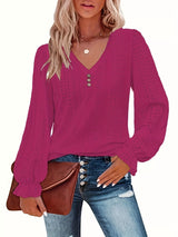 Woman wearing a rose red long-sleeve top with a brown purse on a white background