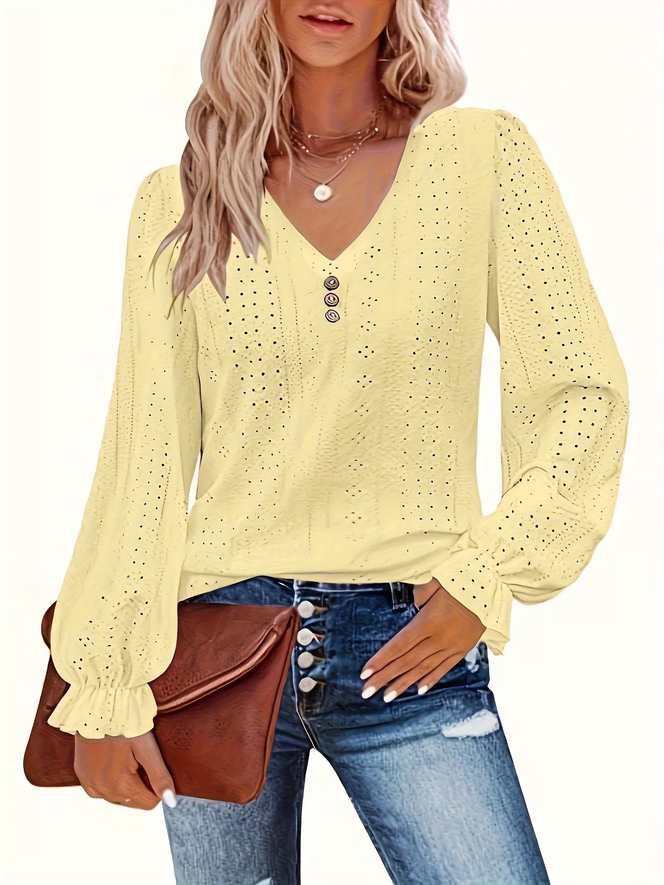 Woman wearing a yellow long-sleeve blouse with a brown clutch and blue jeans.
