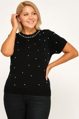 Woman wearing a black sweater with pearl embellishments on a white background