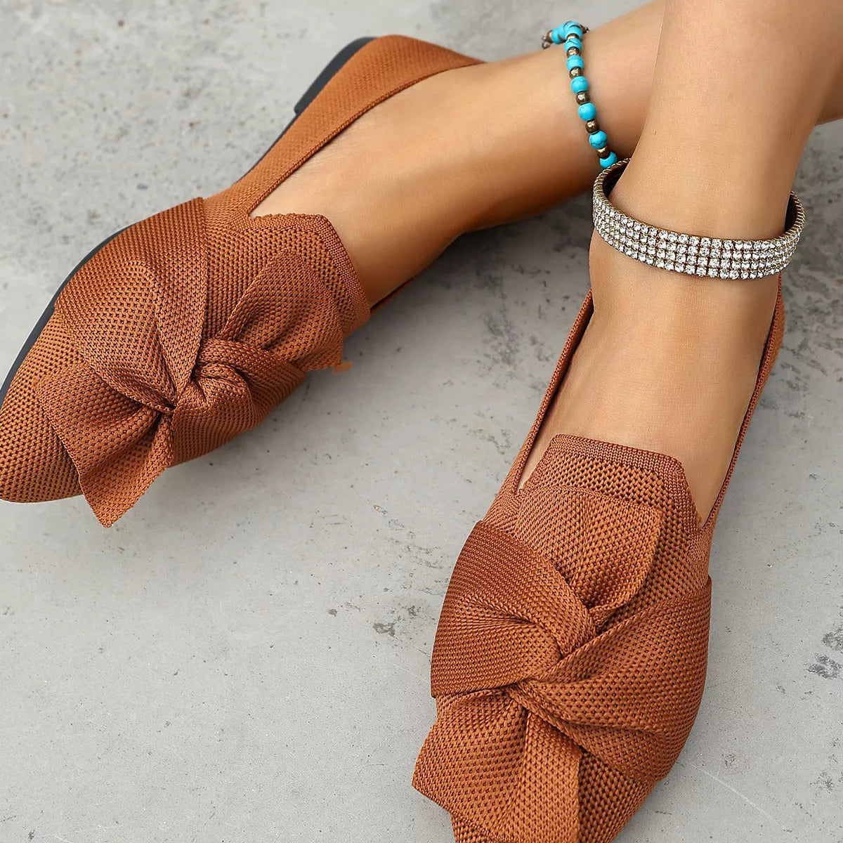 Brown shoes with knotted design worn by a person on a gray surface