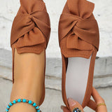 Brown shoes with knotted design held by a person against a light background