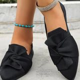Black shoes with large bows worn by a person on a light background