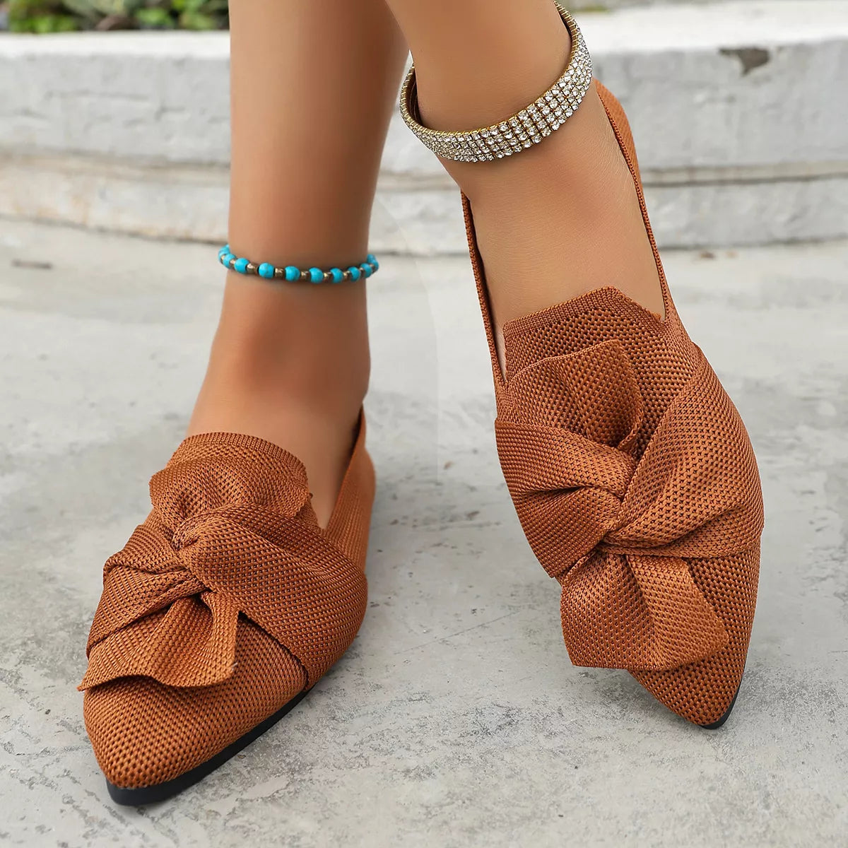 Brown mesh shoes with a bow detail worn by a person on a light background