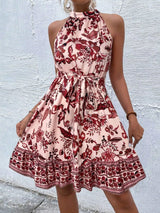 Woman wearing a floral dress against a textured white wall.