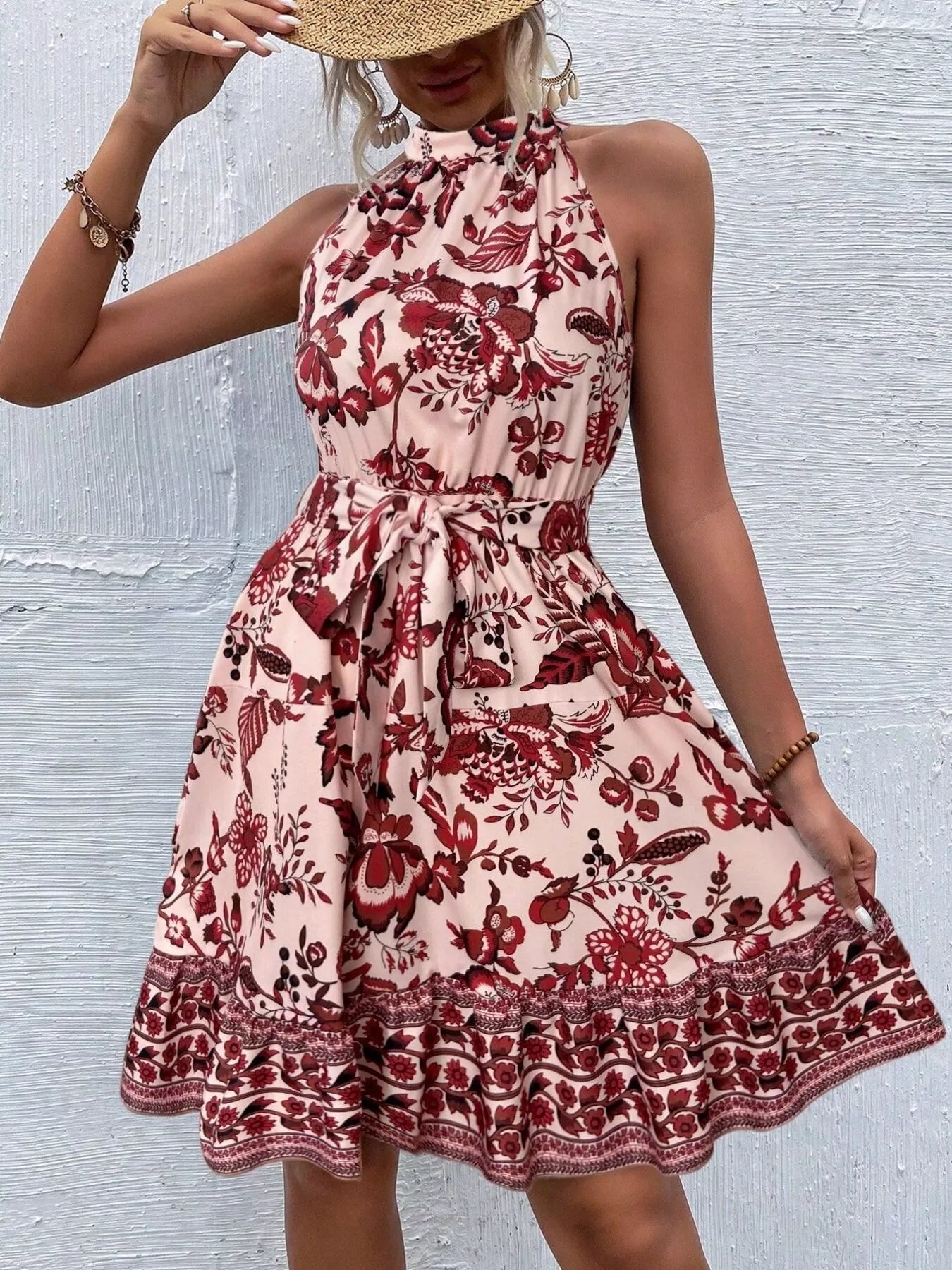 Woman wearing a Burnt Coral floral dress with a textured white background