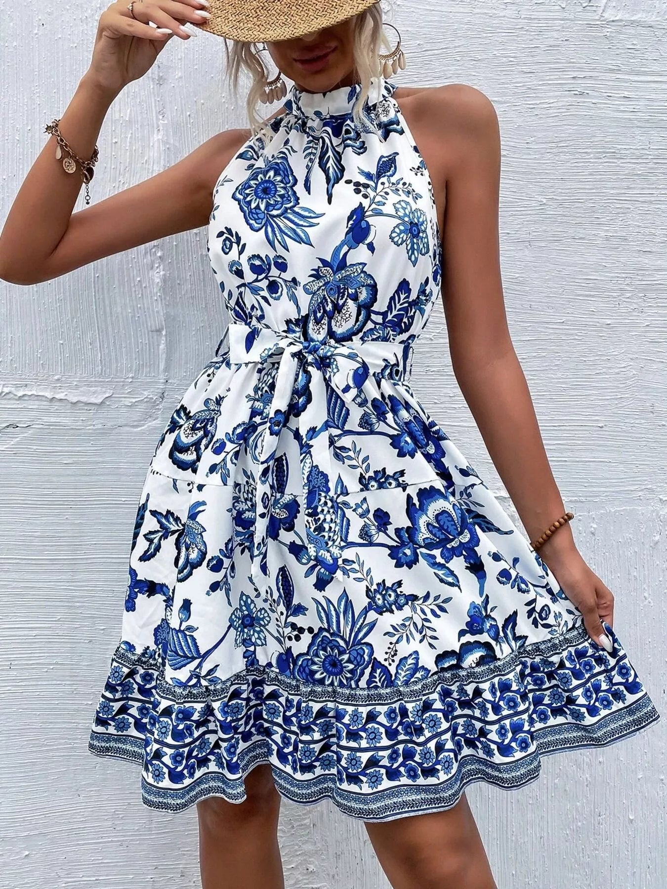 Woman wearing a blue and white floral dress against a light gray background