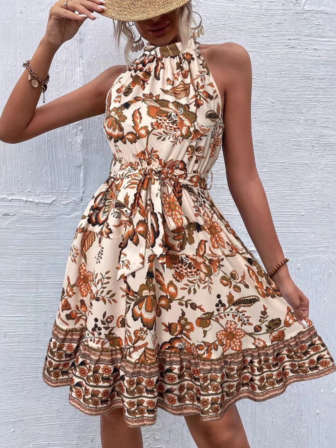 Woman wearing a tan floral dress with a textured wall background
