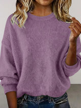 Woman wearing a purple round neck dropped shoulder sweater with dark-wash jeans.