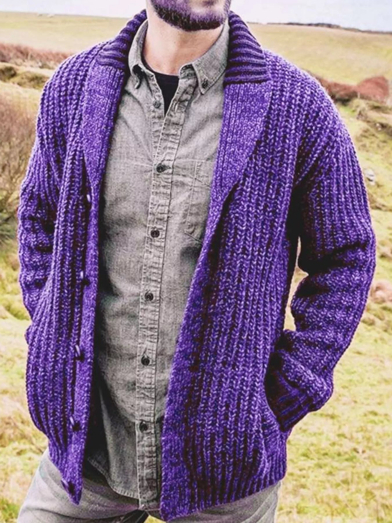 Men's purple chunky knit shawl collar cardigan with button-front closure, ribbed texture, and front pockets, layered over a gray button-down shirt.