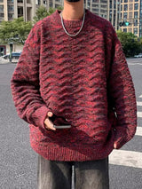 Man wearing an oversized red and dark marled textured knit pullover sweater with crew neckline, long sleeves, and ribbed cuffs and hem.
