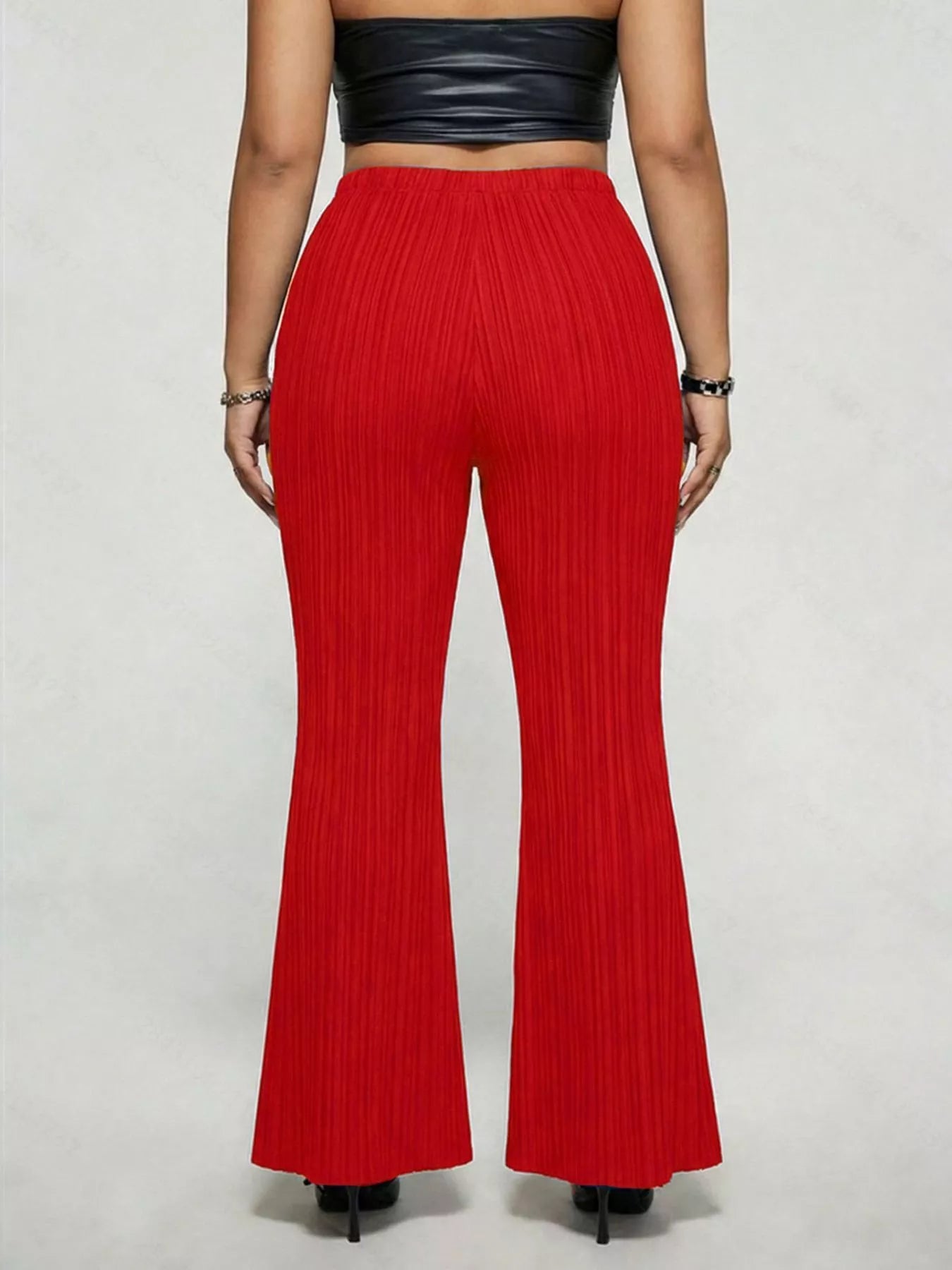 Model wearing red plus-size high-waisted flare pants styled with pointed-toe heels for an elegant and sophisticated look.