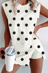 Person wearing a white sleeveless top with black polka dots and matching shorts, holding a white tumbler.