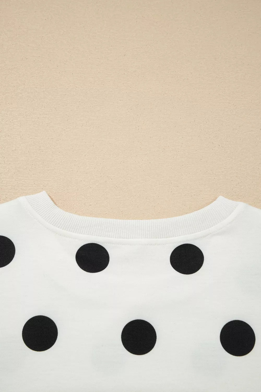 White sweater with black polka dots on a beige background
