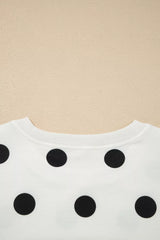 White sweater with black polka dots on a beige background