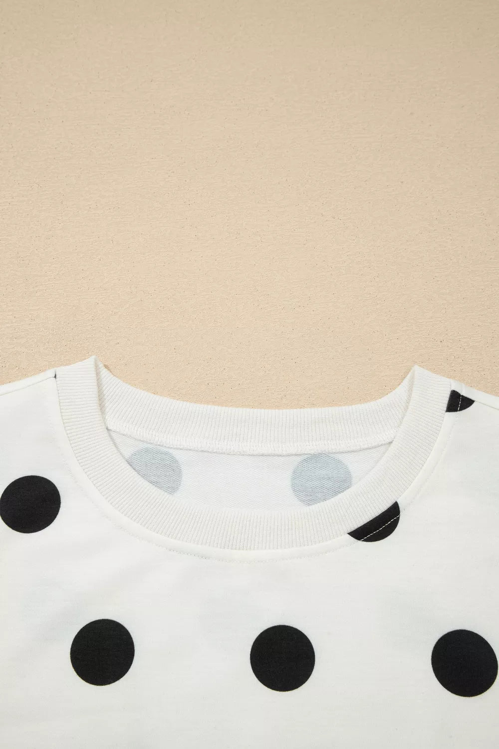 Close-up of a white shirt with black polka dots on a beige background