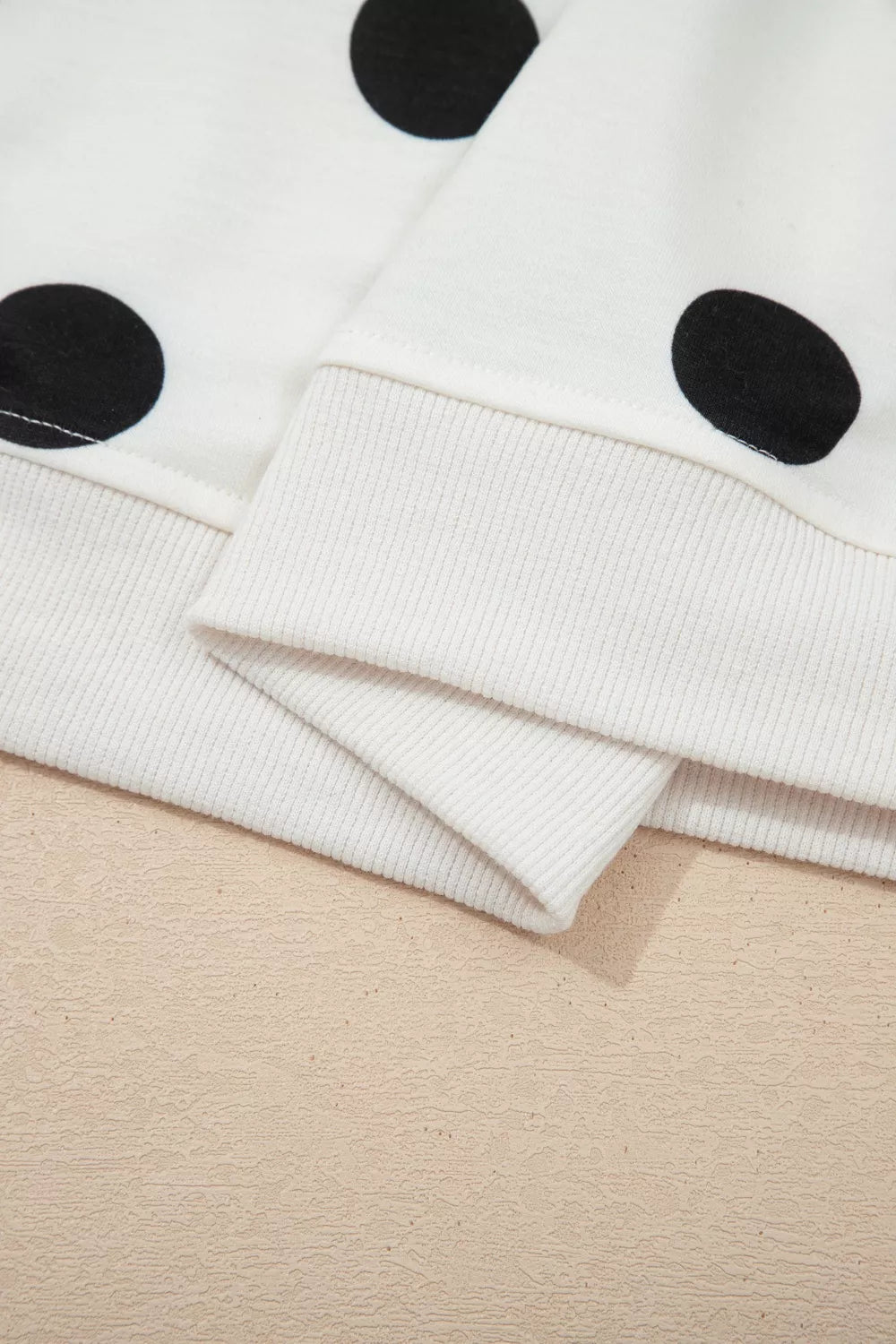 Close-up of a white fabric with black polka dots on a beige surface