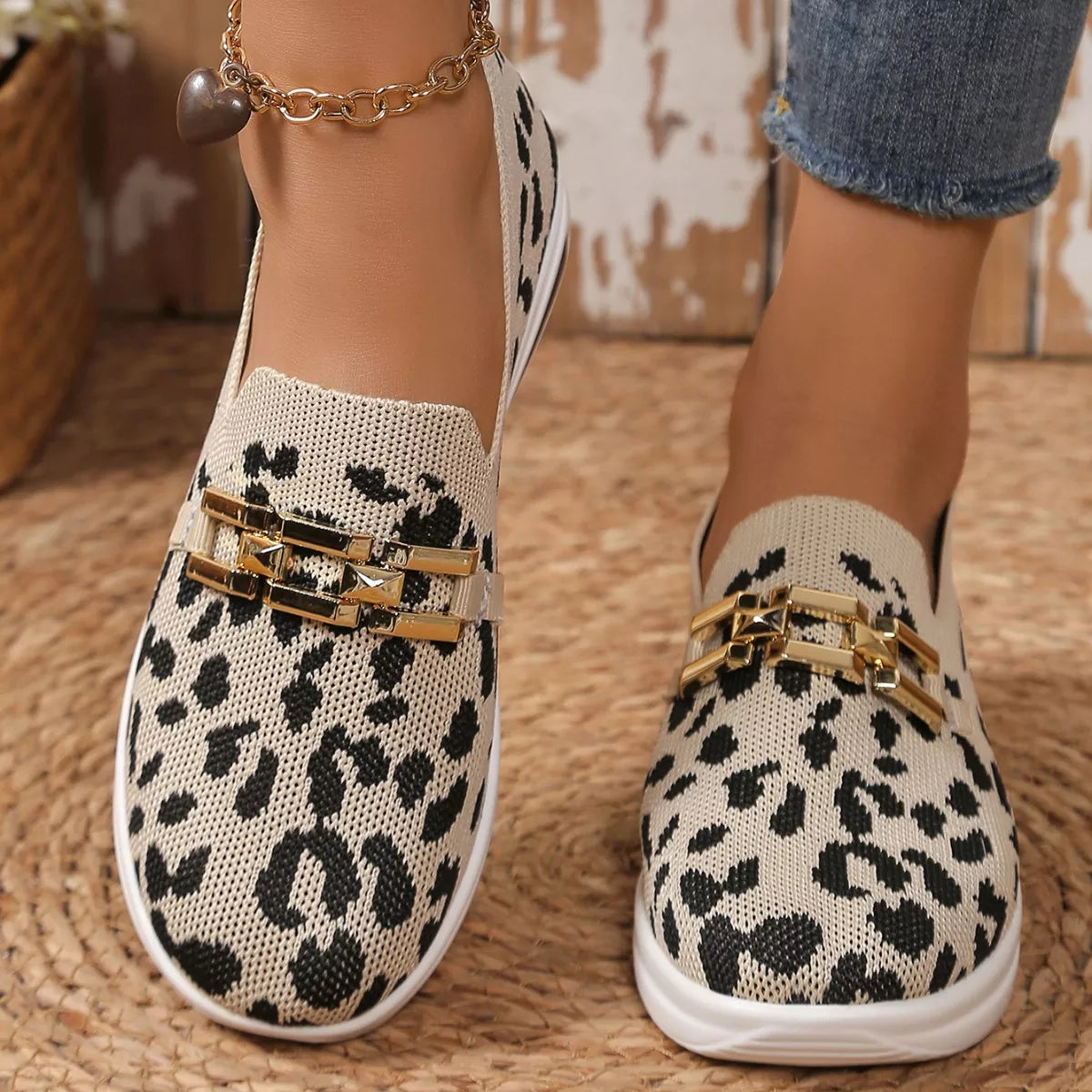 Leopard print loafers with gold accents worn by a person on a woven surface.