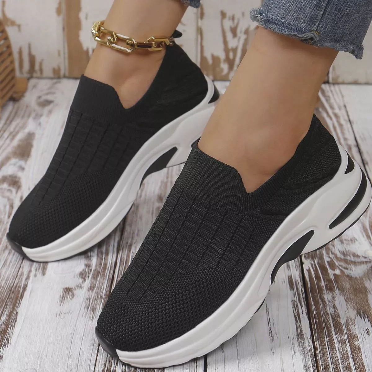 Black women’s round toe mesh slip-on sneakers with a lightweight knit upper and sporty white and black rubber sole.