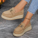 Beige espadrille loafers worn with blue jeans on a gray surface.
