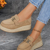 Beige espadrille loafers worn on a gray surface with a blurred background