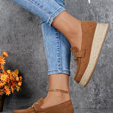 Brown loafers with espadrille sole worn with blue jeans against a gray background