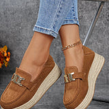 Brown loafers with jute sole worn with rolled-up jeans on a gray background