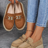 Brown loafers with gold accents held by a person wearing blue jeans.