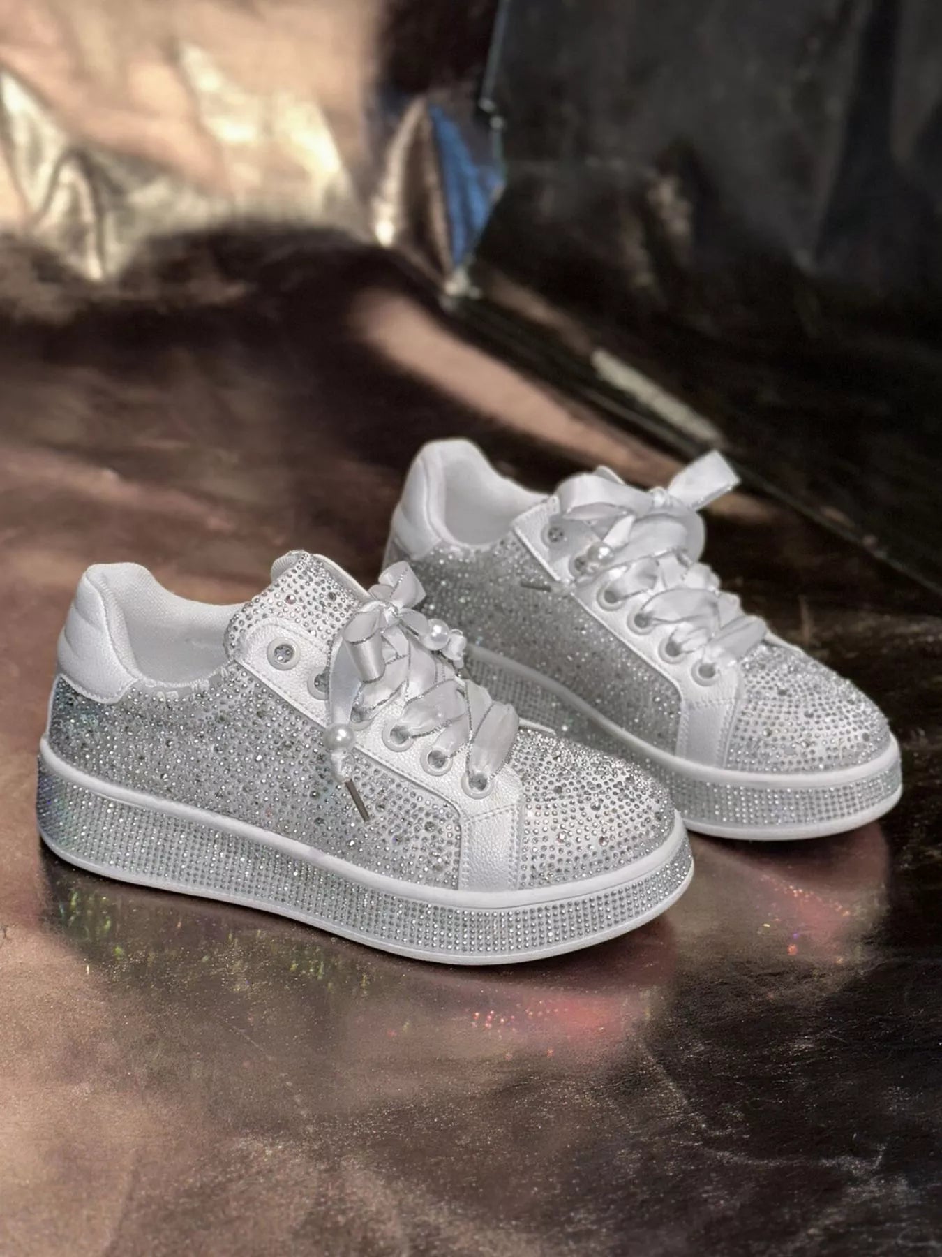White round toe women’s sneakers with rhinestone embellishments, satin-style ribbon laces and pearl-inspired accents.