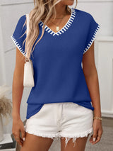Woman wearing a royal blue short sleeve knit top with white contrast trim along the V-neckline and sleeves.
