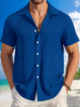 Man wearing a royal blue textured short sleeve button-up shirt with white pants for a polished casual summer look.