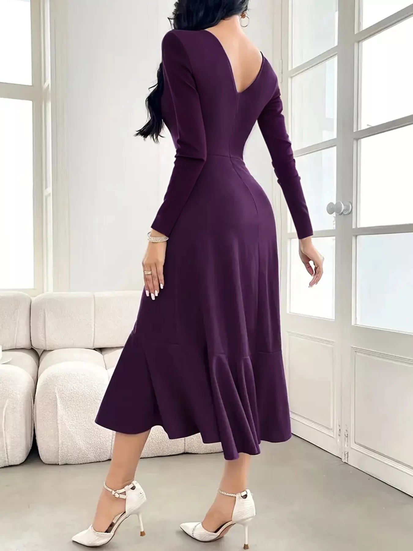 Woman wearing a purple dress in a room with white walls and furniture.