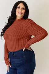 Woman wearing a rust Basic Bae ribbed mock neck long sleeve top with ruched puff shoulders, paired with dark blue jeans.