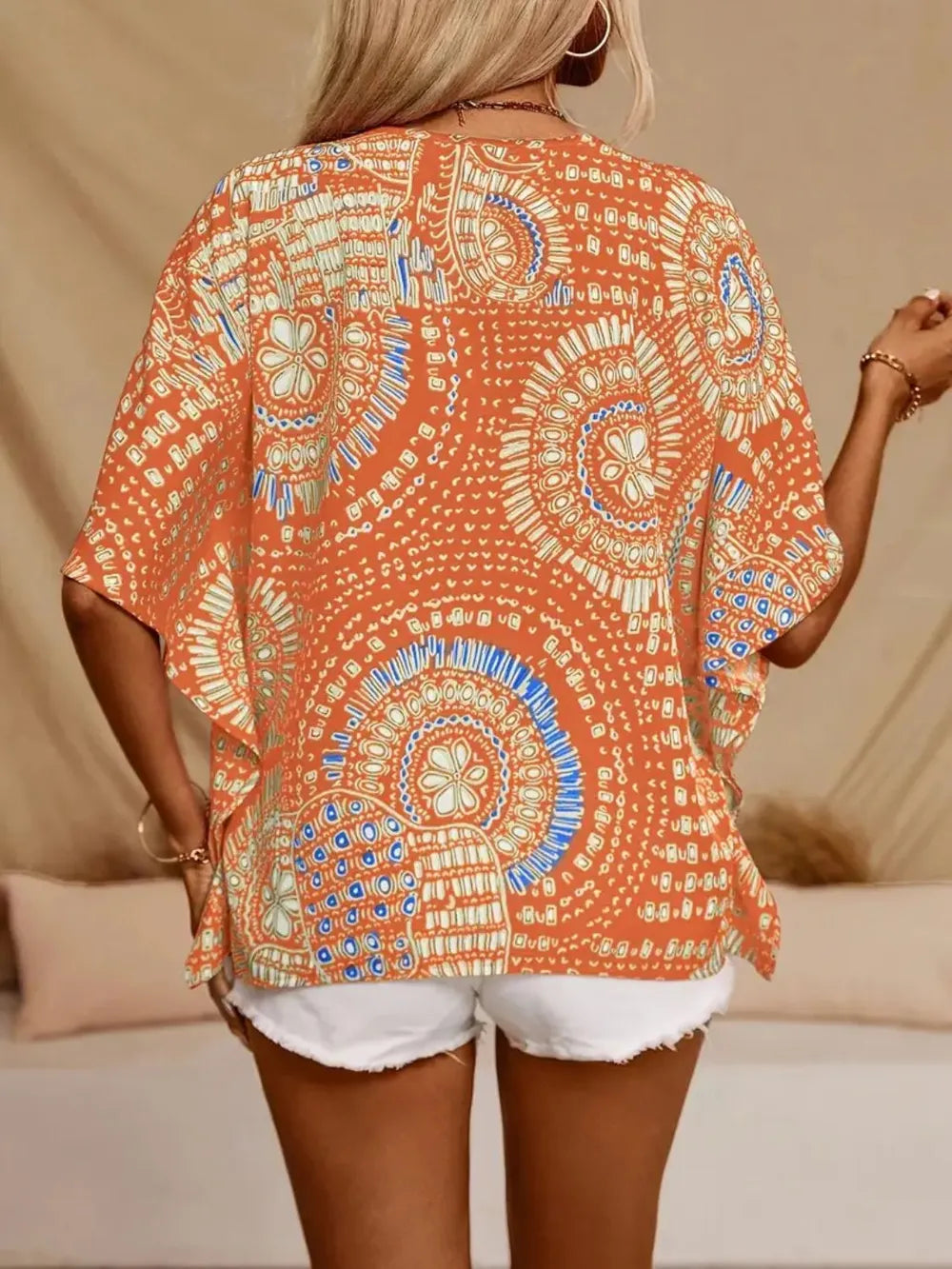 Sherbet printed V-neck top with half sleeves and a relaxed boho-inspired fit paired with white shorts.