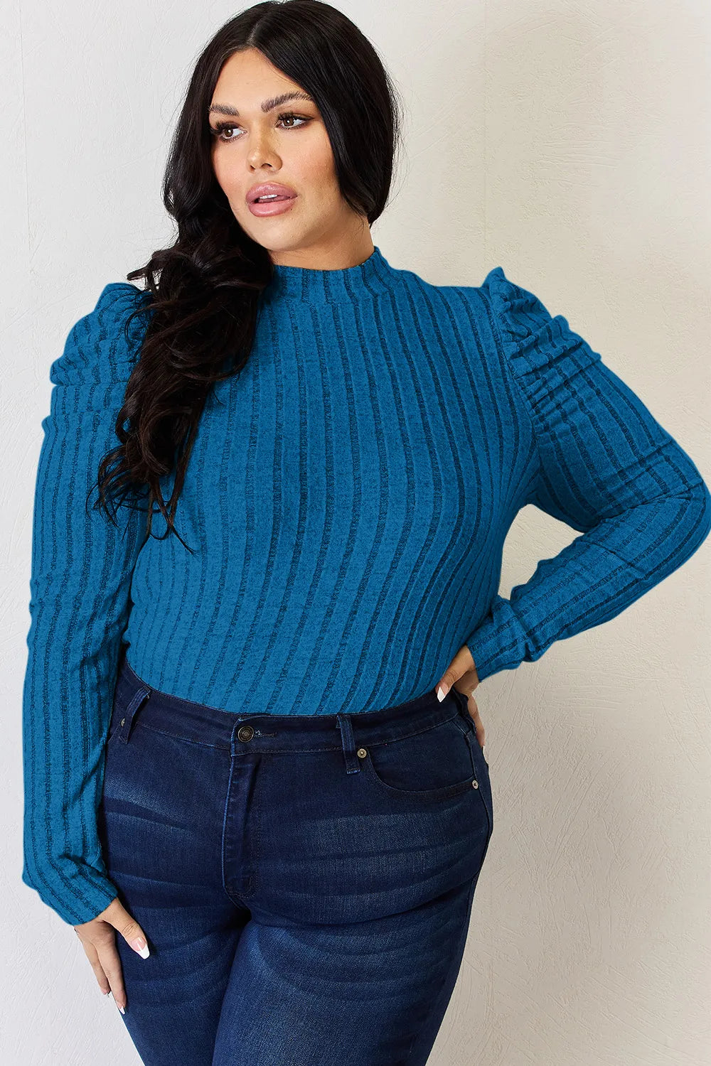 Woman wearing a sky blue Basic Bae ribbed mock neck long sleeve top with ruched puff shoulders, paired with dark blue jeans.