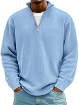 Man wearing a sky-blue ribbed corduroy quarter zip pullover sweatshirt layered over a white shirt.