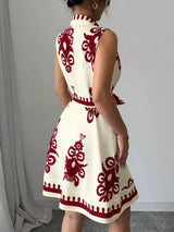 White dress with red patterns worn by a person against a plain background