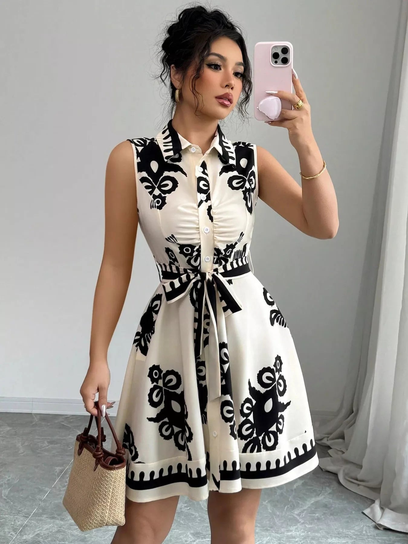 Woman taking a mirror selfie wearing a black and white patterned dress.