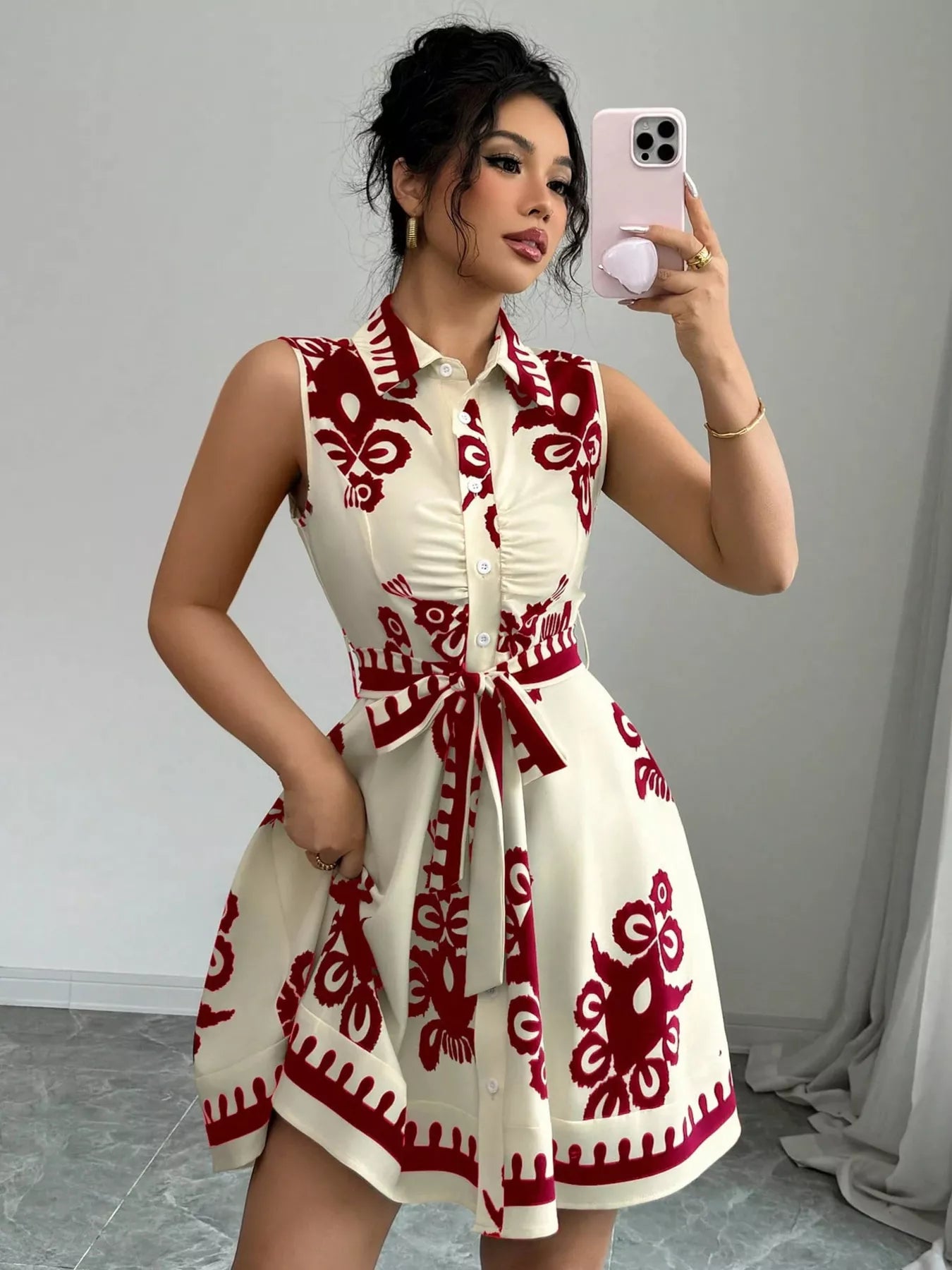 Woman taking a mirror selfie wearing a white dress with red patterns.
