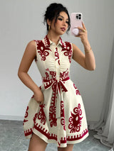Woman taking a mirror selfie wearing a white dress with red patterns.