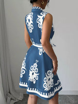 Woman wearing a blue dress with white patterns against a gray curtain background