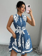 Woman wearing a blue dress with white patterns, taking a mirror selfie.