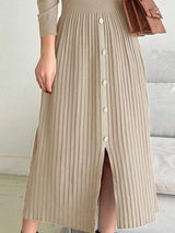 Woman wearing an apricot mock neck long sleeve knit midi dress with pleated skirt, front buttons and slit.