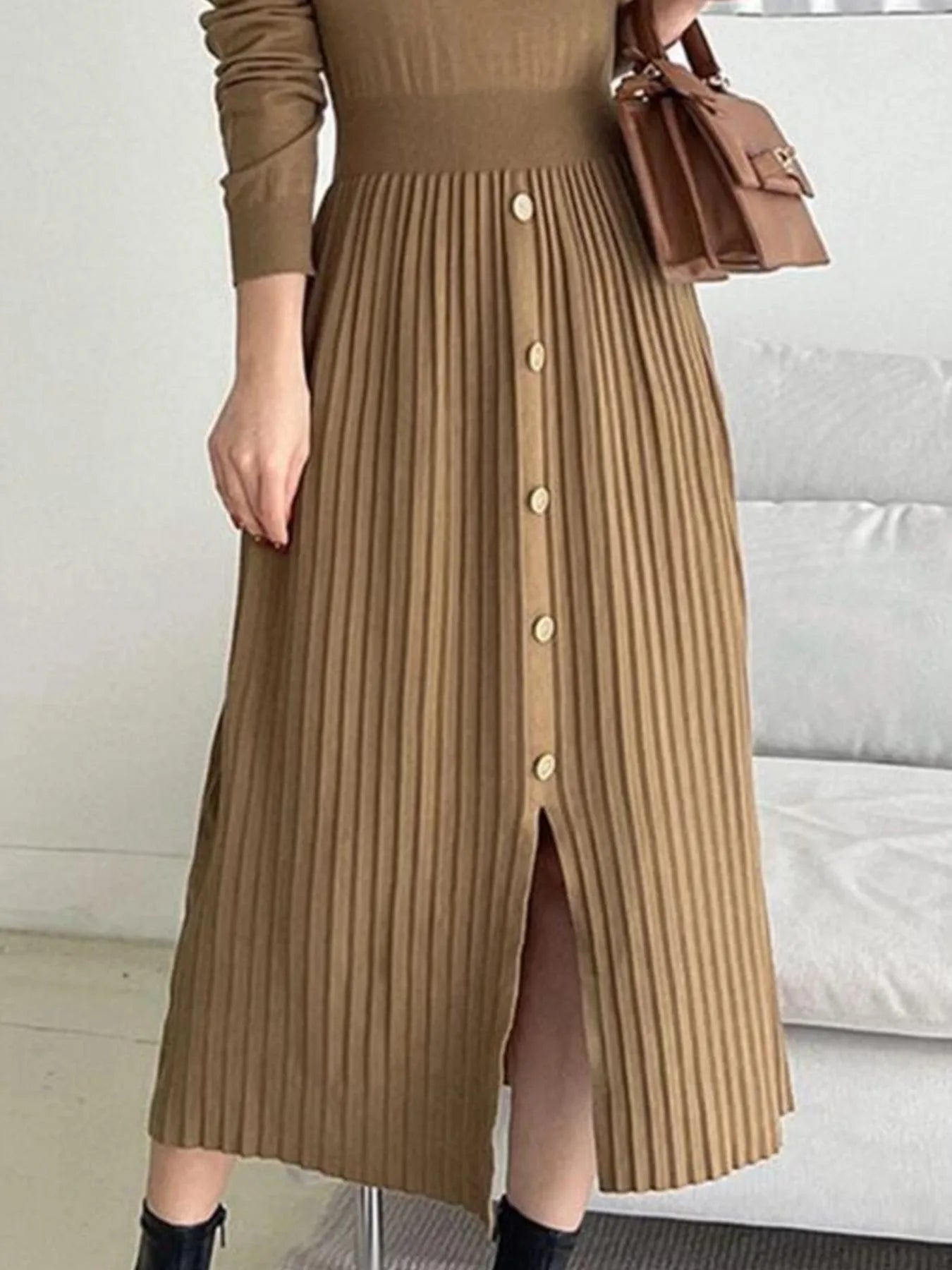 Woman wearing a khaki mock neck long sleeve knit midi dress with pleated skirt, front buttons and slit.