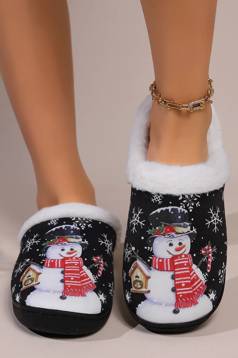 Black snowman round toe slippers with white faux fur trim, festive snowflake print, red scarf design, and black flat soles.
