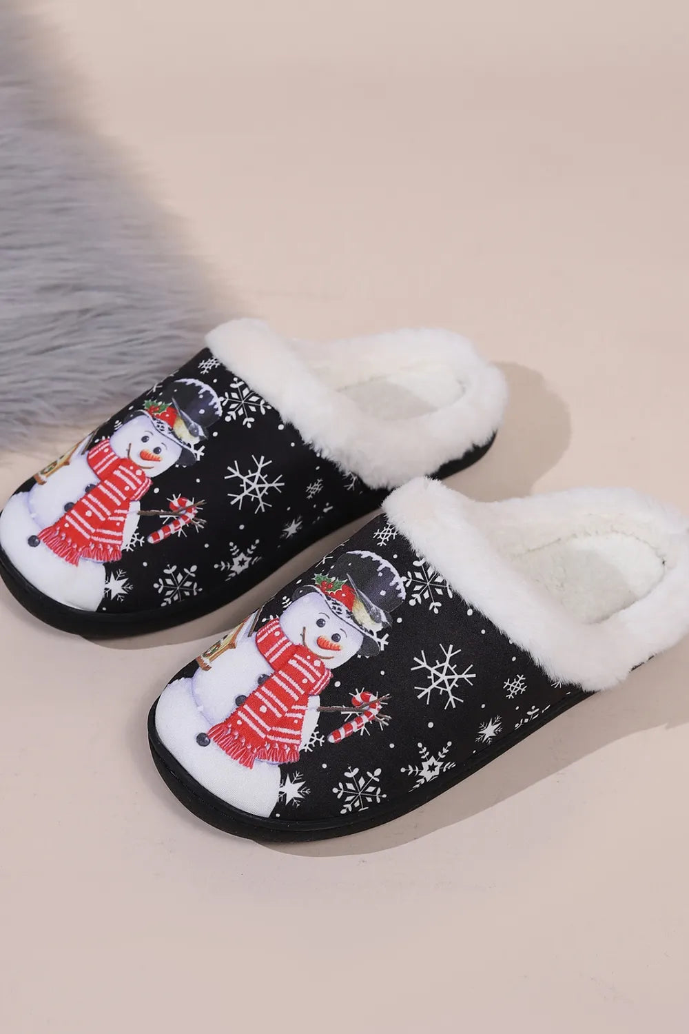 Black snowman round toe slippers with white faux fur trim, festive snowflake print, red scarf design, and black flat soles.