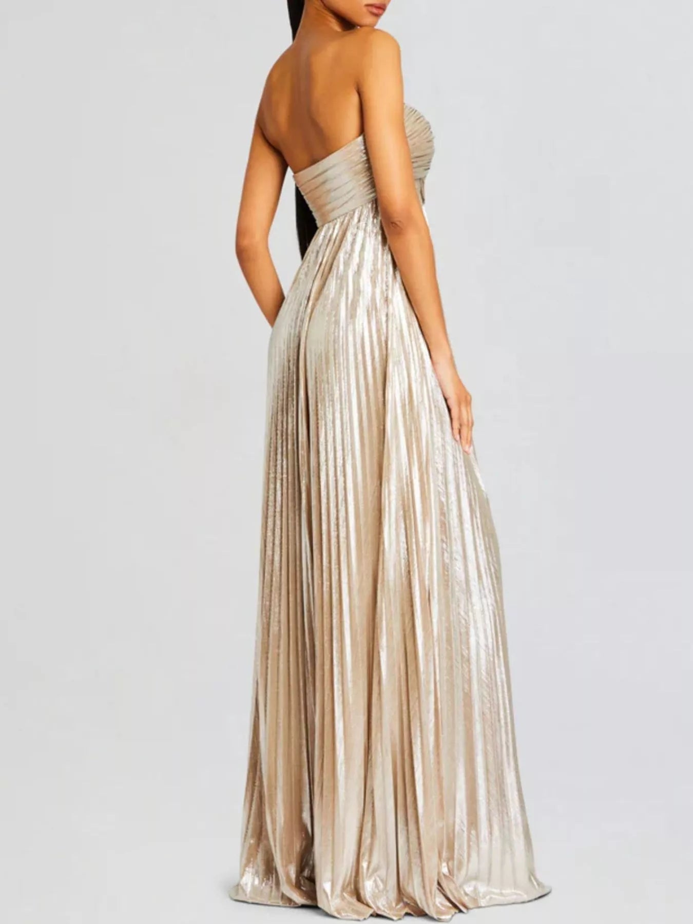 Woman wearing a strapless, long, metallic beige gold dress on a plain background