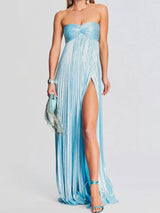 Woman wearing a strapless, floor-length blue dress with a high slit on a white background